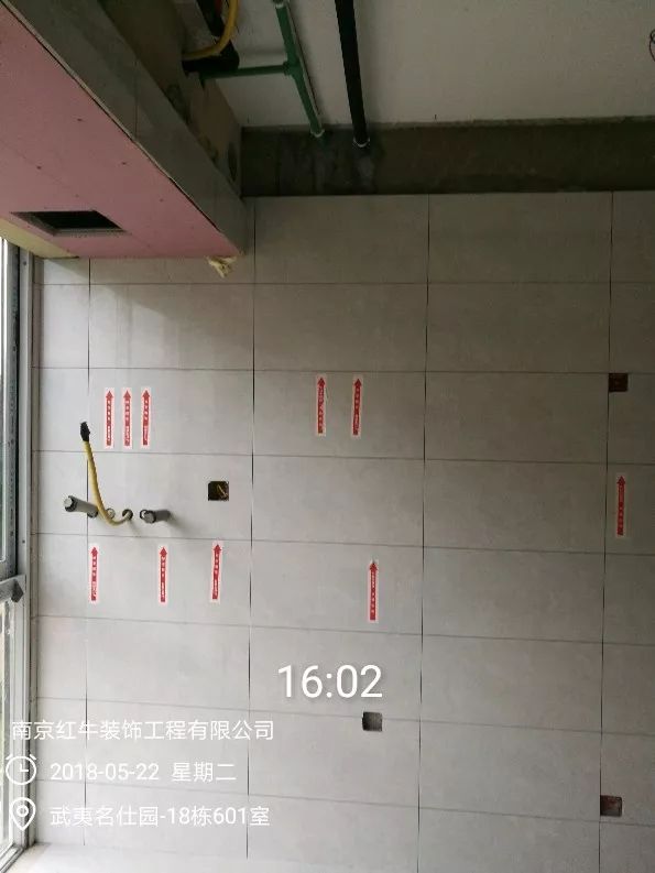 南京武夷名仕園124平米簡(jiǎn)美風(fēng)格裝修  享受家?guī)淼臏囟?0五月份_墻磚鋪貼完成后，紅牛裝飾的工人會(huì)用專用護(hù)角條對(duì)瓷磚角保護(hù)，用標(biāo)貼標(biāo)出水管、線管走向示意。